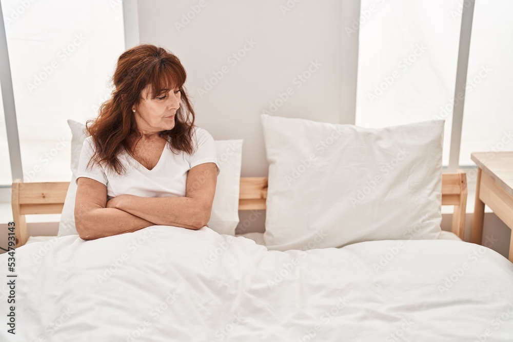 Middle age woman sitting on bed with worried expression at bedroom Middle age woman sitting on bed with worried expression at bedroom