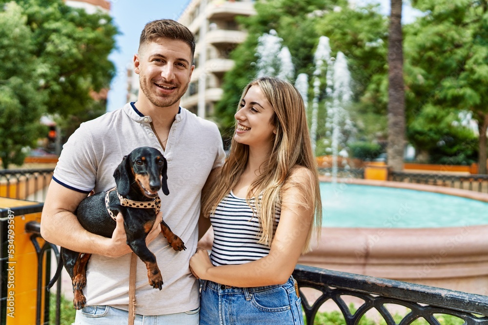 Young caucasian couple hugging and smiling happy standing with dog at the city.