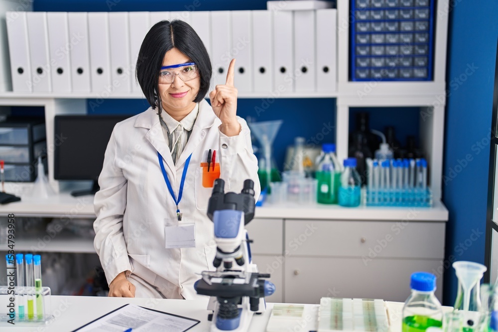 Young asian woman working at scientist laboratory pointing finger up with successful idea. exited and happy. number one. Young asian woman working at scientist laboratory pointing finger up with successful idea. exited and happy. number one.