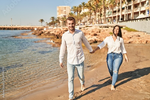 Man and woman couple smiling happy walking at seaside