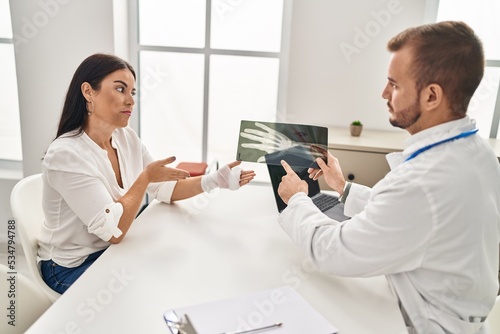 Man and woman doctor and patient having medical consultation holding xray at clinic