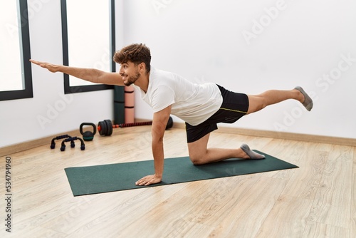 Young arab man smiling confident stretching at sport center