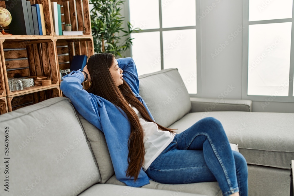 © Krakenimages.com - Young chinese girl relaxed with hands on head sitting on the sofa at home. © Krakenimages.com - Young chinese girl relaxed with hands on head sitting on the sofa at home.