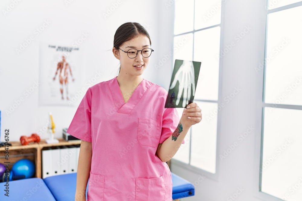 Young asian woman holding hand xray at physiotherapy clinic Young asian woman holding hand xray at physiotherapy clinic