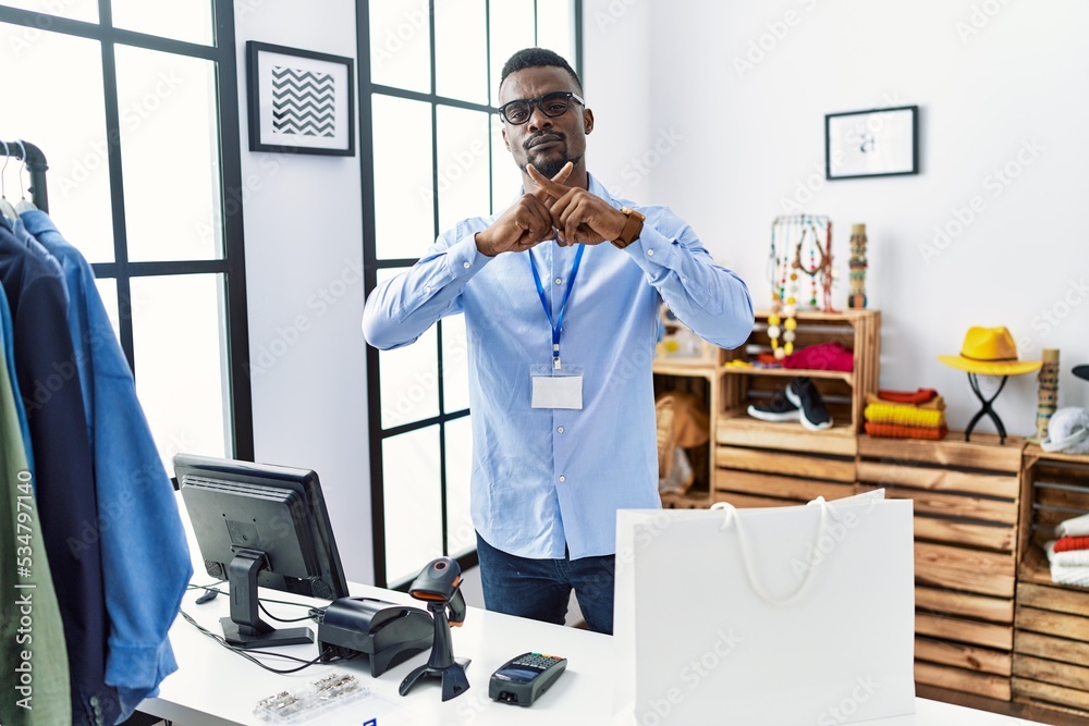 Young african man working as manager at retail boutique rejection expression crossing fingers doing negative sign Young african man working as manager at retail boutique rejection expression crossing fingers doing negative sign