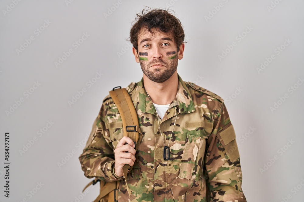 Hispanic young man wearing camouflage army uniform depressed and worry for distress, crying angry and afraid. sad expression.
