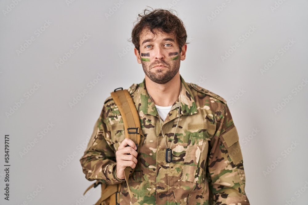 Hispanic young man wearing camouflage army uniform depressed and worry for distress, crying angry and afraid. sad expression. Hispanic young man wearing camouflage army uniform depressed and worry for distress, crying angry and afraid. sad expression.