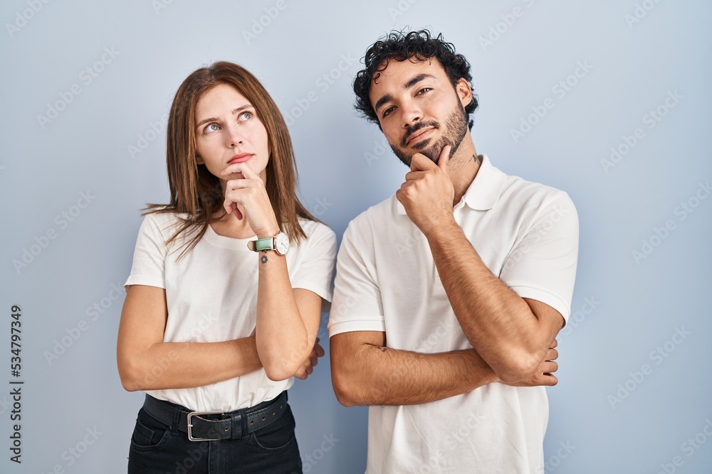 Young couple wearing casual clothes standing together looking confident at the camera smiling with crossed arms and hand raised on chin. thinking positive. Young couple wearing casual clothes standing together looking confident at the camera smiling with crossed arms and hand raised on chin. thinking positive.