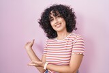 Young middle east woman standing over pink background inviting to enter smiling natural with open hand