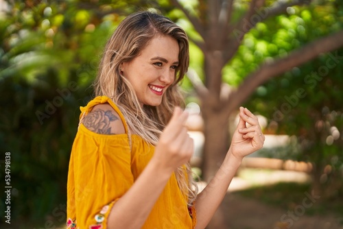 Young woman smiling confident doing spend money gesture at park