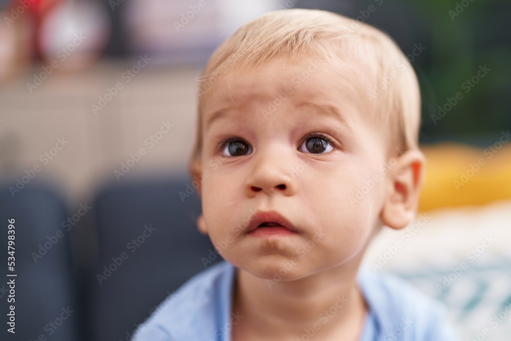 Adorable toddler sitting on sofa with relaxed expression at home Adorable toddler sitting on sofa with relaxed expression at home