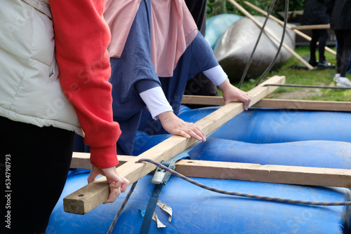 Mädchen bauen ein Floß aus Holz und Fässern 