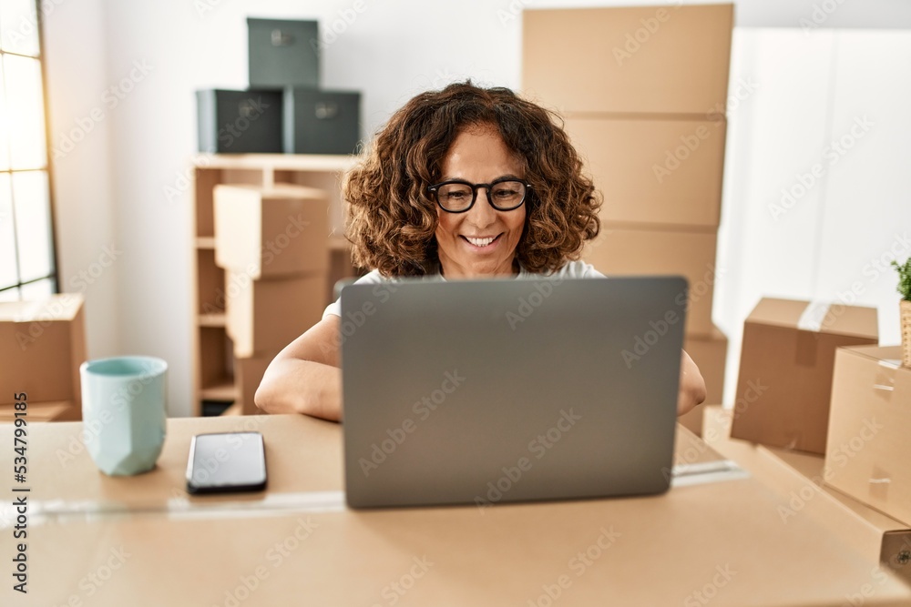 Middle age hispanic woman smiling confident using laptop at new home Middle age hispanic woman smiling confident using laptop at new home