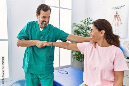 Middle age man and woman smiling confident stretching arm having rehab session at physiotherapy clinic