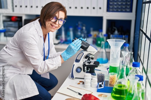 Fototapeta Naklejka Na Ścianę i Meble -  Middle age woman scientist using microscope at laboratory