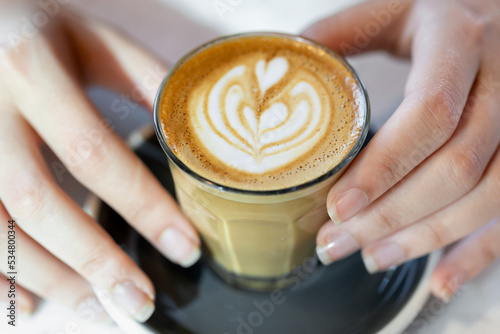 Aromatic cup of coffee in female hands, overhead closeup view