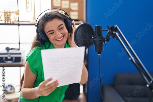 Young hispanic woman artist singing song at music studio