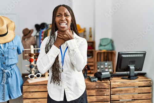 Black woman with braids working as manager at retail boutique shouting and suffocate because painful strangle. health problem. asphyxiate and suicide concept.