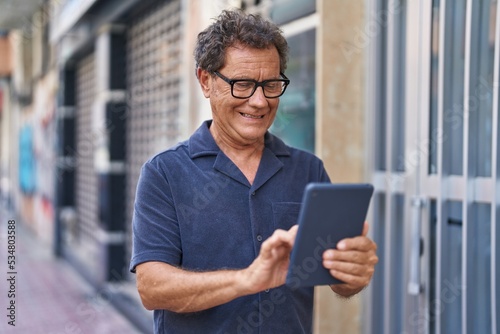 Middle age man smiling confident using touchpad at street