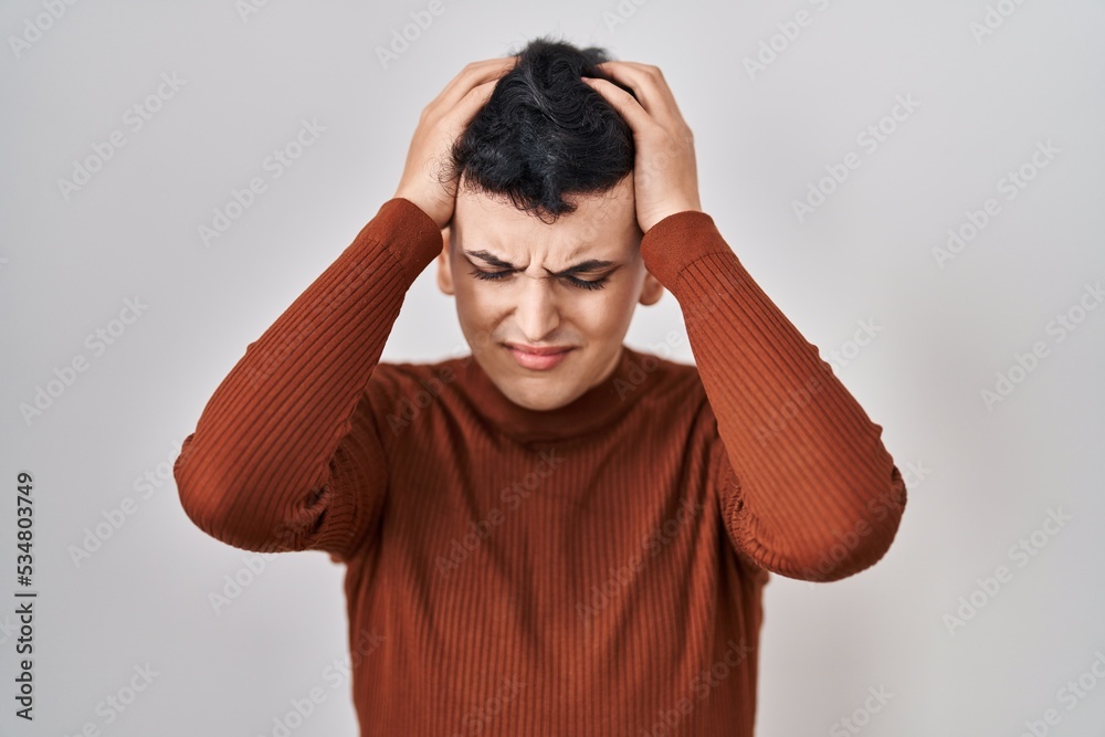 Non binary person wearing make up standing over isolated background suffering from headache desperate and stressed because pain and migraine. hands on head. Non binary person wearing make up standing over isolated background suffering from headache desperate and stressed because pain and migraine. hands on head.