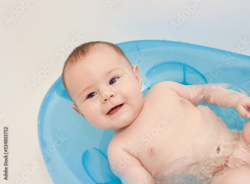 Little baby taking a bath in a blue baby tubh