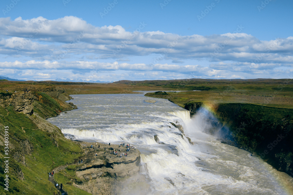 water falls in Iceland's volcanic region on a sunny day with rainbow