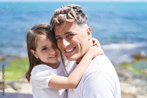 Father and daughter smiling confident hugging each other at seaside