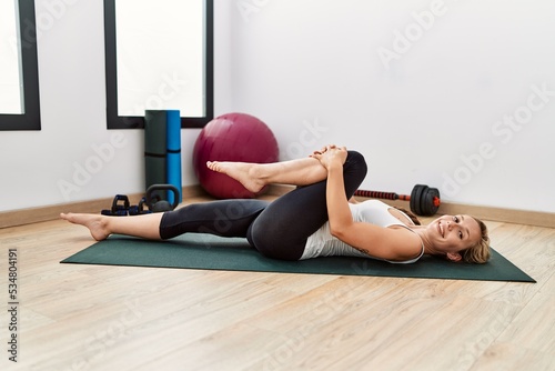 Young caucasian woman smiling confident stretching at sport center