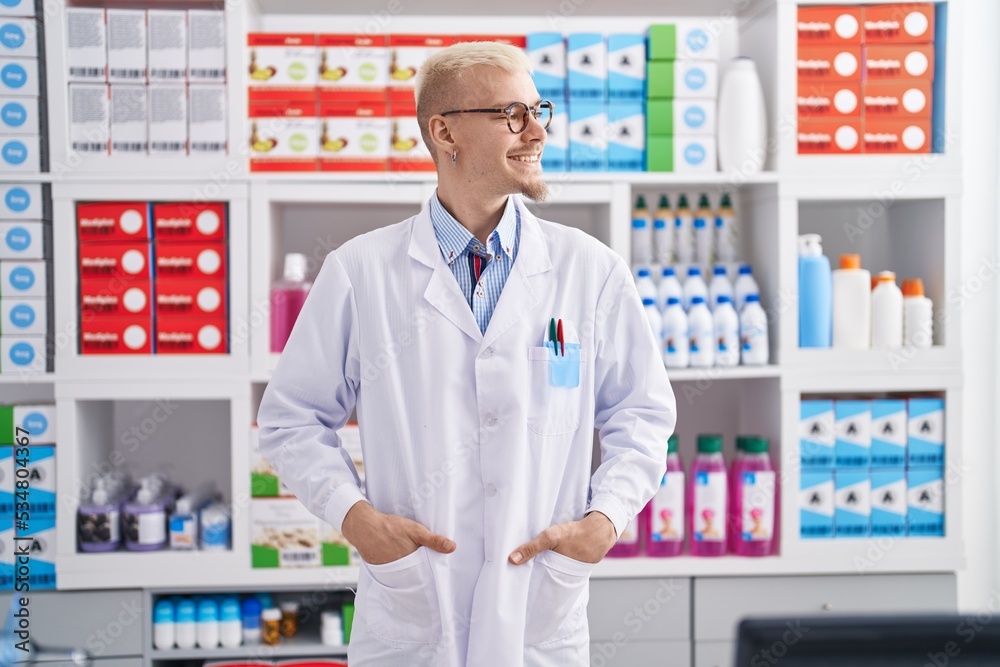 Young caucasian man pharmacist smiling confident standing at pharmacy