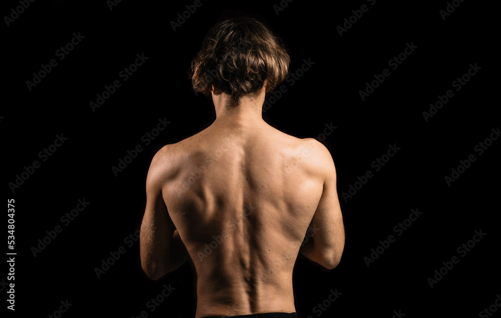 athletic muscular back of a man on a dark background. athletic muscular back of a man on a dark background.