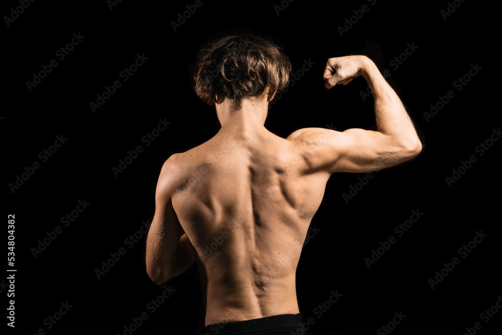 athletic muscular back of a man on a dark background.