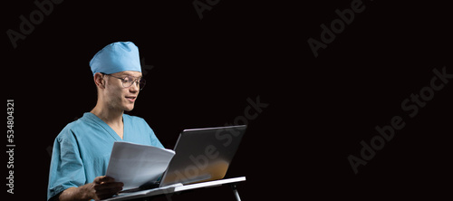 male doctor scientist speaks while looking into a laptop monitor on a dark background. The concept of online education and consultations in medicine