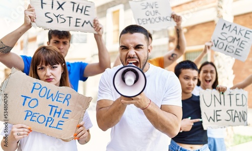 Group of young activists protesting holding banner and using megaphone at the city. © Krakenimages.com