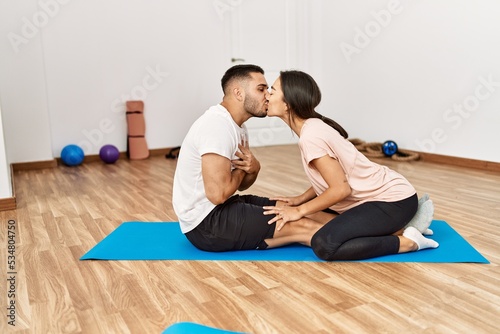 Latin man and woman couple kissing training abs exercise at sport center