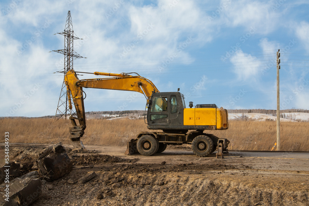 Obraz premium A working excavator with attachments on the construction of a road junction.