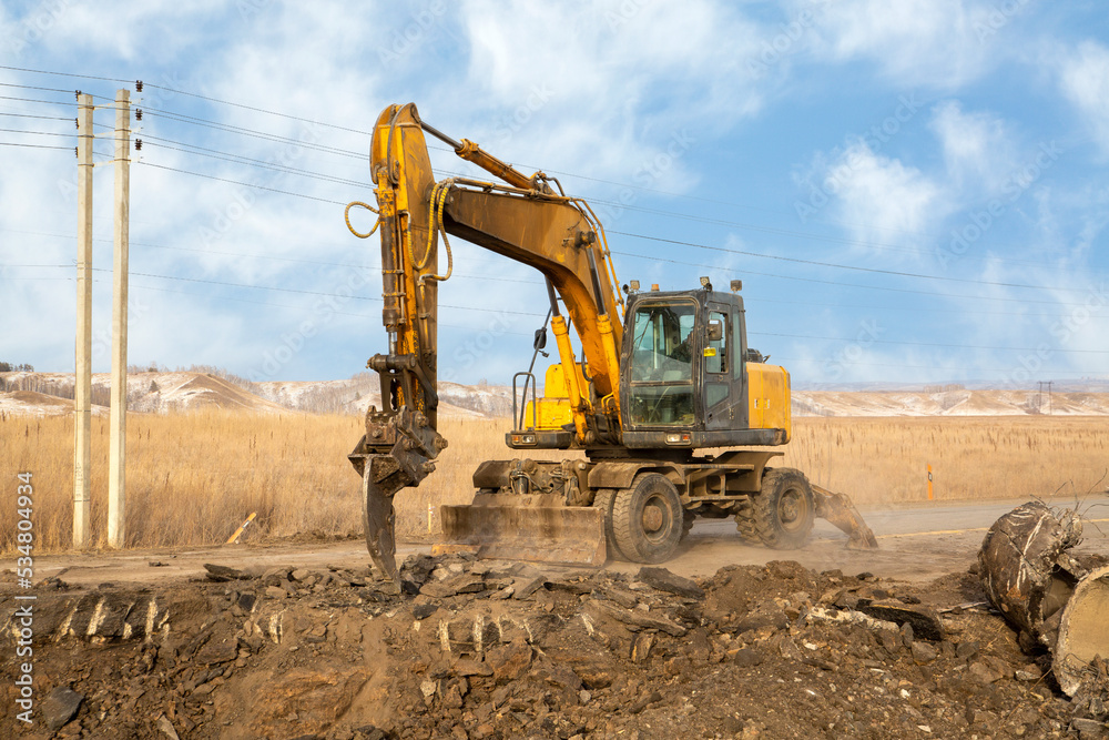 A working excavator with attachments on the construction of a road junction. A working excavator with attachments on the construction of a road junction.