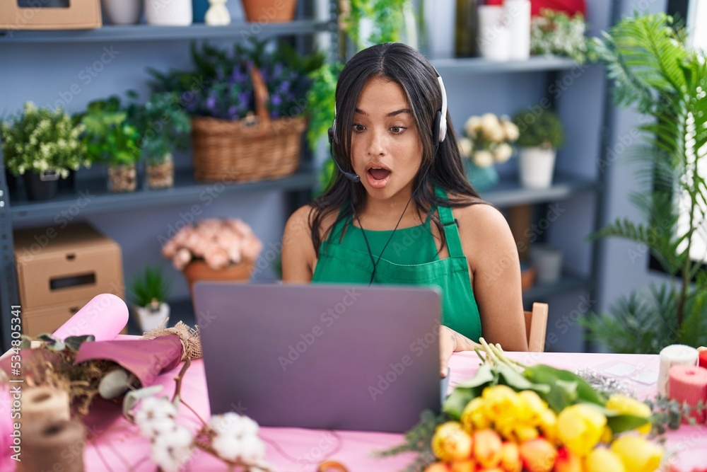 Brunette woman working at florist shop doing video call scared and amazed with open mouth for surprise, disbelief face Brunette woman working at florist shop doing video call scared and amazed with open mouth for surprise, disbelief face