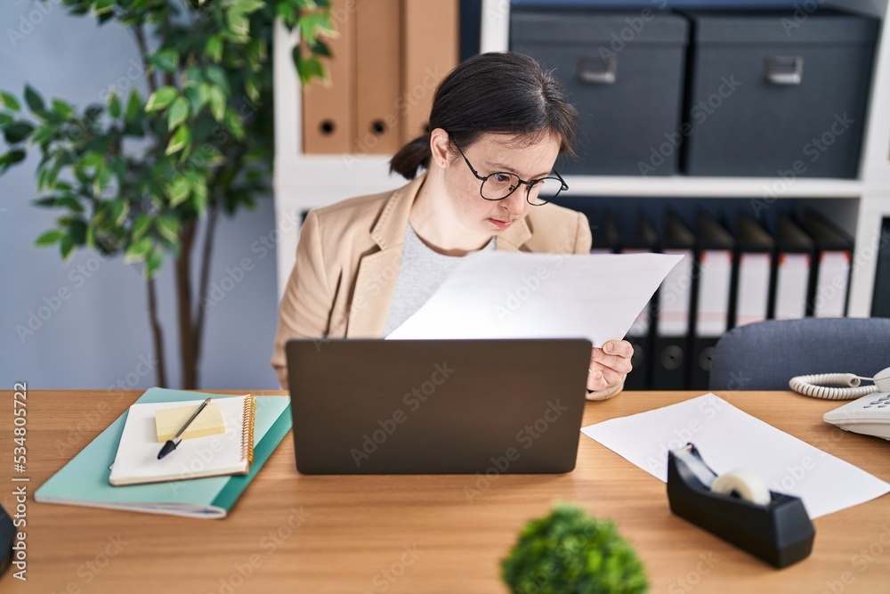 Young woman with down syndrome business worker reading document working at office Young woman with down syndrome business worker reading document working at office