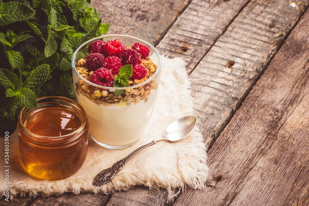 Glass of homemade yogurt with granola and raspberries.