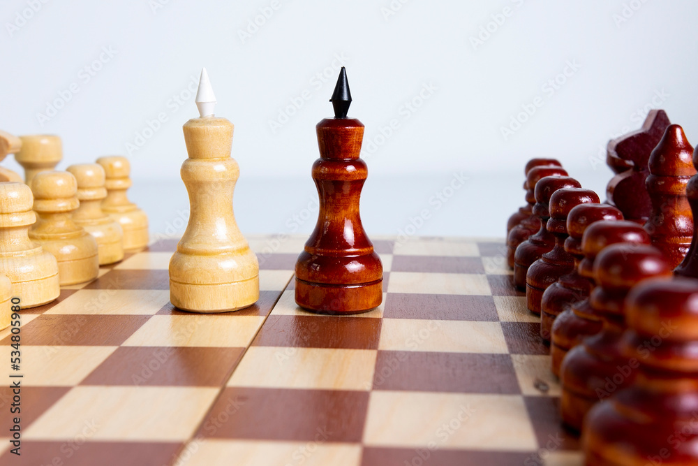 Intellective game. All figures on the chessboard, close-up two kings. Black and white kings facing each other on a chessboard.