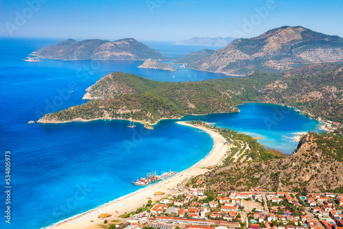 Obraz na płótnie Summer sunny day in blue lagoon surrouded by mountains, Oludeniz (Turkey). Amaizing view from mountain to turistic city Oludeniz. Beautiful view on summer sea with ships. w salonie