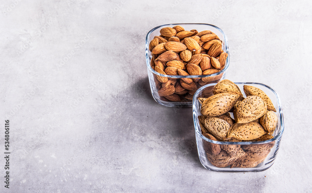 Shelled almonds and almonds in shell. Bowls with almonds copy space.