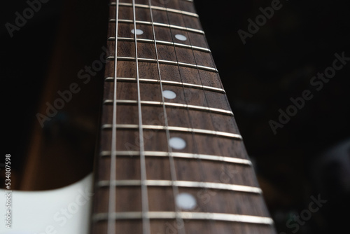 A close up of a guitar neck and body indoors during the day