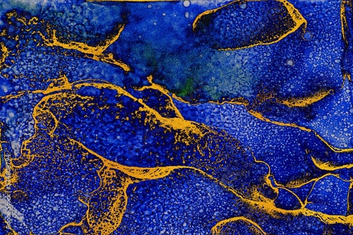 Splash of blue and white ink and golden dust filled lines on Alcohol ink fluid abstract texture fluid art with gold glitter and liquid.