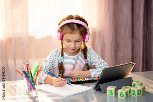 An elementary school girl learns mental arithmetic online from home. Education.