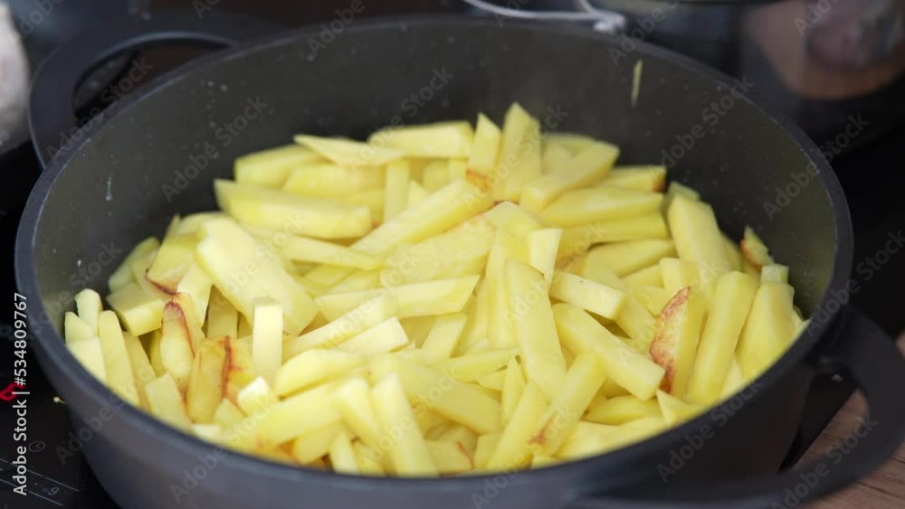 Close-up cooking potatoes. Cooking fried potatoes. A woman's hand stir fried potatoes with spatula in a frying pan. Close-up cooking potatoes. Cooking fried potatoes. A woman's hand stir fried potatoes with spatula in a frying pan.