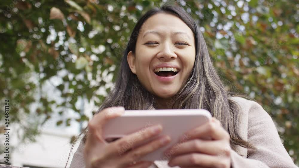 Young attractive female laughs at something she sees on her phone out in the city, in slow motion Young attractive female laughs at something she sees on her phone out in the city, in slow motion