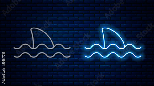 Glowing neon line Shark fin in ocean wave icon isolated on brick wall background. Vector