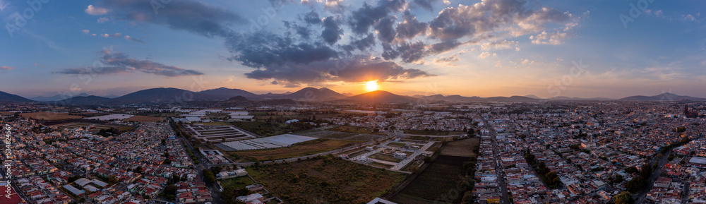 Aerial: epic sunset in the mountains and the city. Drone view
