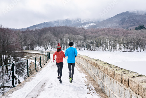 Couple running in winter nature on seawall